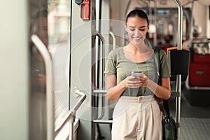 Joyful Passenger Woman Texting On Mobile Phone In Modern Tram