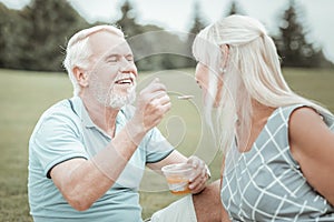Joyful pensioner having picnic on nature with wife