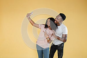 Joyful people using mobile phone to take selfies together in studio.