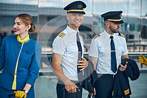 Joyful pilots and stewardess standing on the street