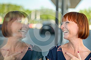 Joyful playful woman laughing and pointing to her reflection