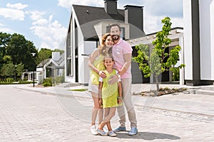 Joyful pleasant man hugging his wife and daughter