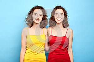 Joyful positive stylish twins in red and yellow tops