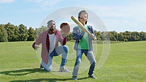 Joyful preadolescent black boy and joyful father playing baseball outdoors