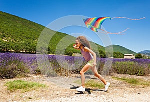 Joyful preteen girl running with rainbow kite