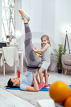 Joyful pretty girl holding her mothers legs