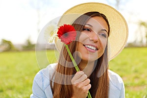 Joyful pretty romantic girl holds two flowers in her hand smile and looking to the side in city park