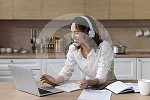 Joyful pretty student girl in wireless headphones watching learning webinar