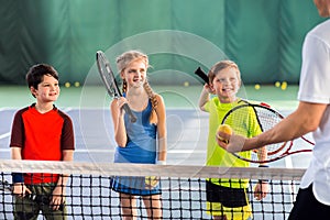 Joyful pupils learning to play tennis