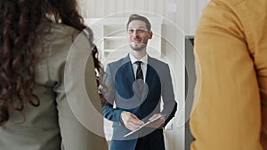 Joyful real estate broker giving keys to happy customers shaking hands indoors in new house