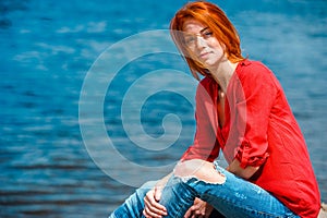 Joyful redhead woman sitting comfortably and smiling photo