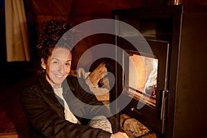 Joyful and relaxed woman sitting next to fireplace.