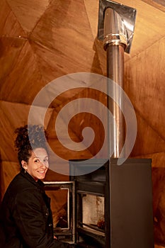 Joyful and relaxed woman sitting next to fireplace.