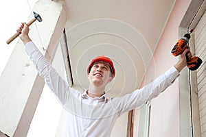 Joyful repairman with hammer and screwdriver