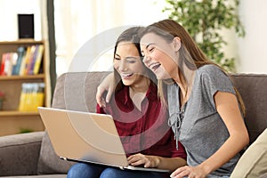 Joyful roommates watching videos in a laptop