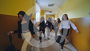 Joyful schoolgirls run after the end of the lessons in the school corridor.