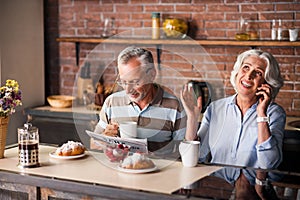 Joyful senior citizen couple drinking coffee together in the kitchen