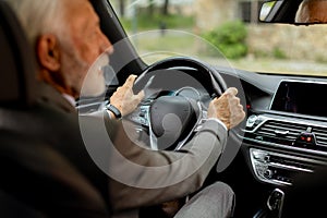 Joyful senior gentleman enjoying a leisurely drive in his modern car on a sunny day photo
