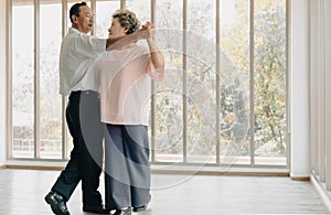 Joyful senior married couple looking at each other eyes dancing at leisure time.