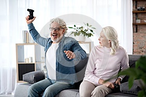 Mature married couple playing video game at home