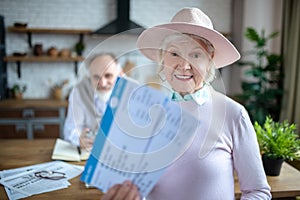 Joyful senior woman holding two boarding passes