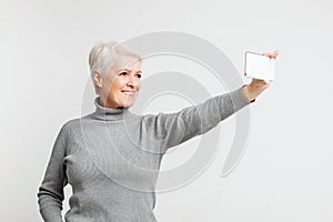 Joyful senior woman taking a selfie with smartphone