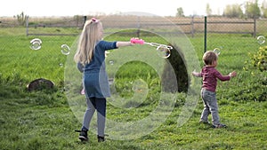 Joyful siblings playing with soap bubbles outdoors