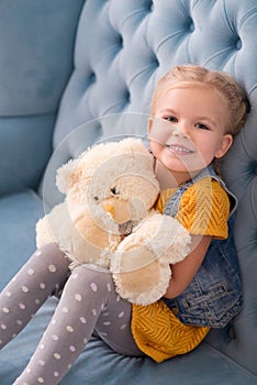 Joyful small girl holding a teddy bear