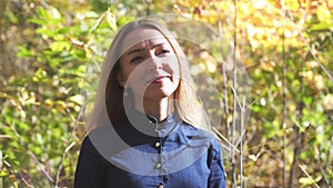 Joyful smiling beauty young blond woman in autumn colorful park, enjoying autumn foliage with a smile. Slow motion