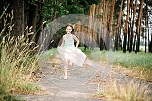 Joyful smiling child girl runs to a meeting on a path in the forest. Happy childhood