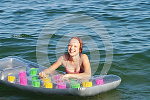 Joyful smiling teenage girl bathes with air mattress in the sea
