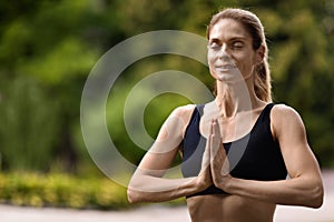 Joyful sporty woman having meditation at park, copy space