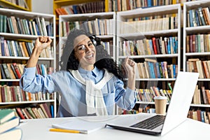 Joyful student celebrating success in a library setting