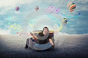 Joyful student guy seated relaxed on the floor listening to a song on headphones