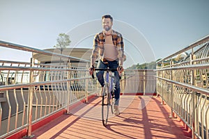 Joyful successful man cycling on sunny day