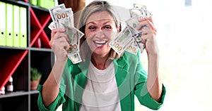 Joyful successful rich girl holding money in office