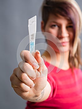 Joyful and surprised woman showing pregnancy test