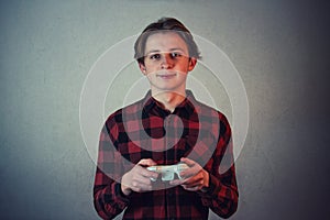 Joyful teen boy playing video games isolated on grey wall background. Excited adolescent holding joystick console looking