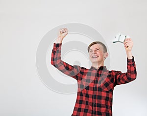 Joyful teenage boy playing video games isolated over white background celebrating success raising hands up while holding the
