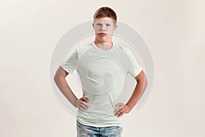 Joyful teenaged disabled boy with Down syndrome making funny faces at camera while posing isolated over white background