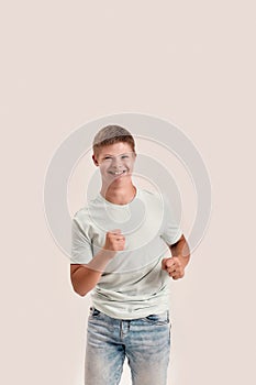 Joyful teenaged disabled boy with Down syndrome smiling at camera while moving forward isolated over white background