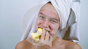 Joyful teenager with acne eating apple after bath