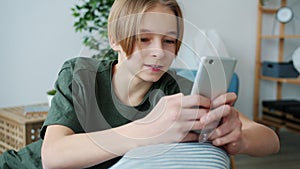 Joyful teenager texting with smartphone enjoying social media communication in apartment