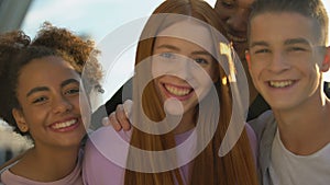 Joyful teenagers hugging female friend smiling on camera, adolescent wellness