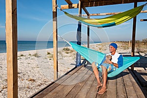 Joyful traveler with funny dog relaxing in a hammock