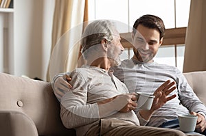 Joyful two generations family sharing news with cup of tea.