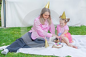 Joyful two girls sisters celebrating their dog\'s birthday with tasty cake in the garden.