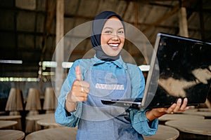 joyful veiled asian woman using computer laptop with showing thumbs up