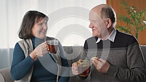 joyful wife and her loving husband have fun and laugh while having tea in living room