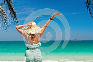 joyful woman with arm up on beach in summer during holidays travel.